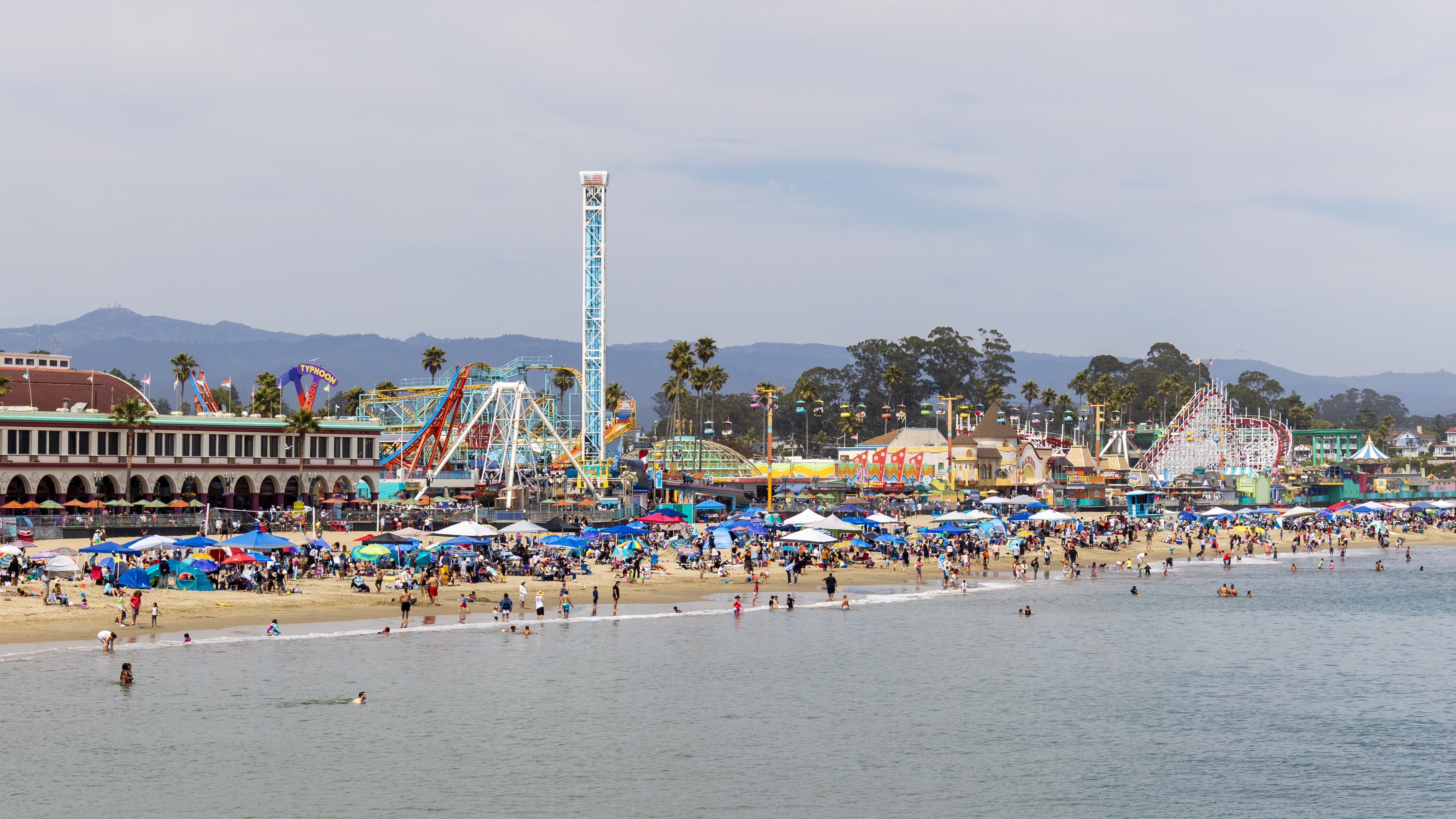 Santa Cruz Beach Boardwalk viewed across the water with the beach, amusement rides, and Giant Dipper along the shoreline